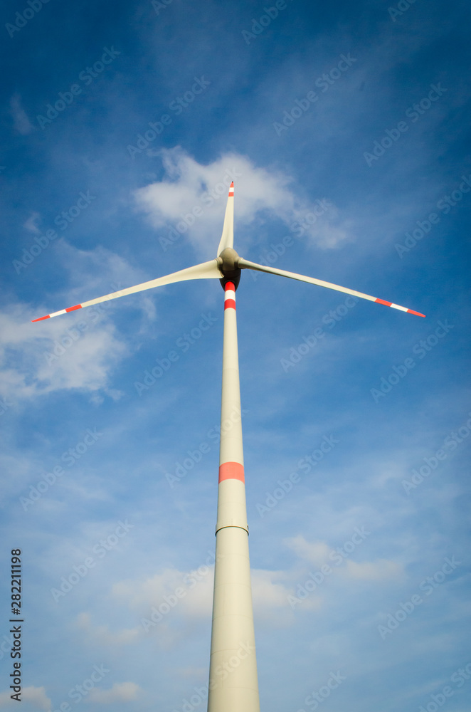 Un'elica di un parco eolico vista dal basso si staglia contro il cielo e le nuvole