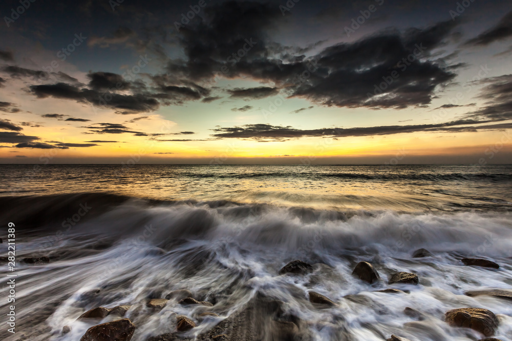 White waves crashing on the rocks at sunset