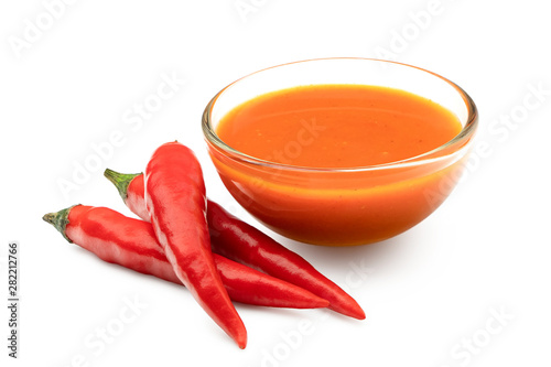Peri peri chilli sauce in a glass bowl next to three red chillies isolated on white. photo