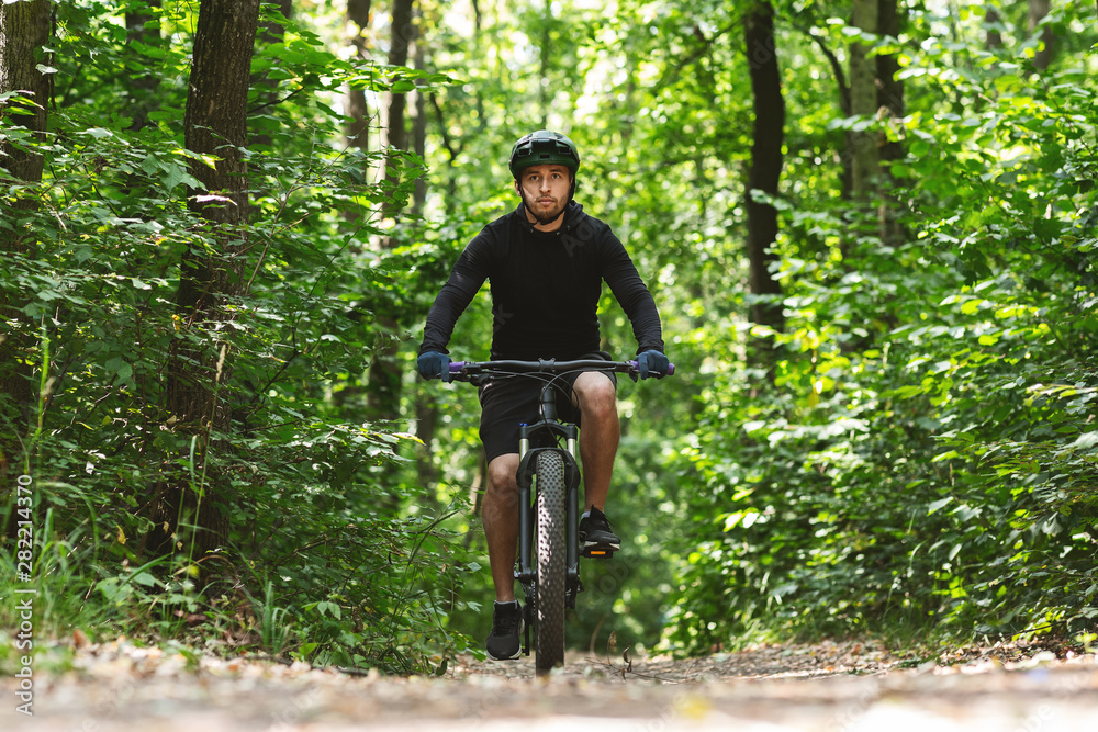 Caucasian man riding bike down the forest trail