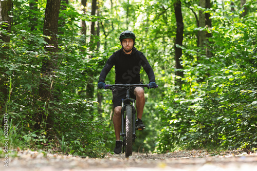 Caucasian man riding bike down the forest trail