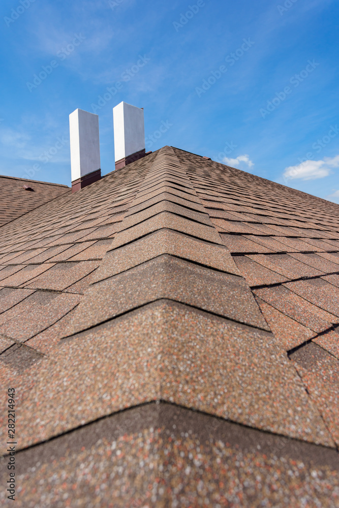 Naklejka premium Asphalt tile roof with chimney on new home under construction