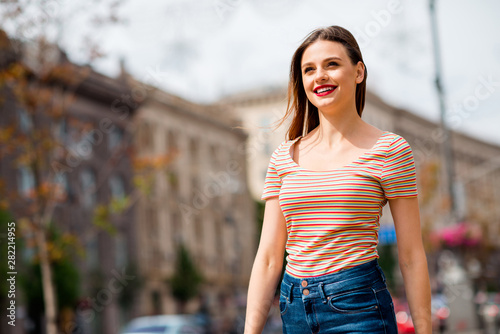 Portrait of lovely lady with foxy ginger hair looking with toothy smile in street town