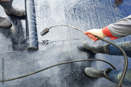 Professional installation of waterproofing on the concrete foundation Two worker at construction site.