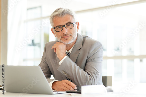 Mature businessman sitting at desk looking at camera