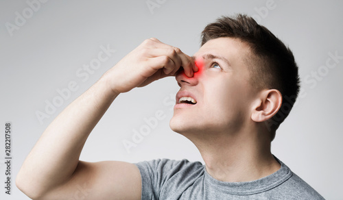 Young man touching his bleeding nose, panorama