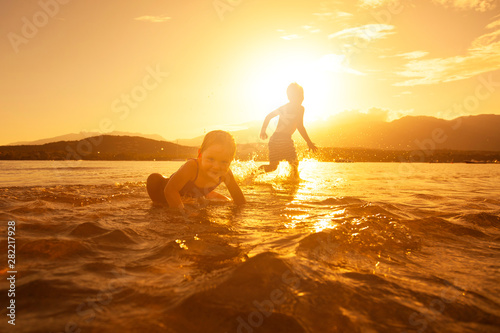cheerful children play in the sea at sunset