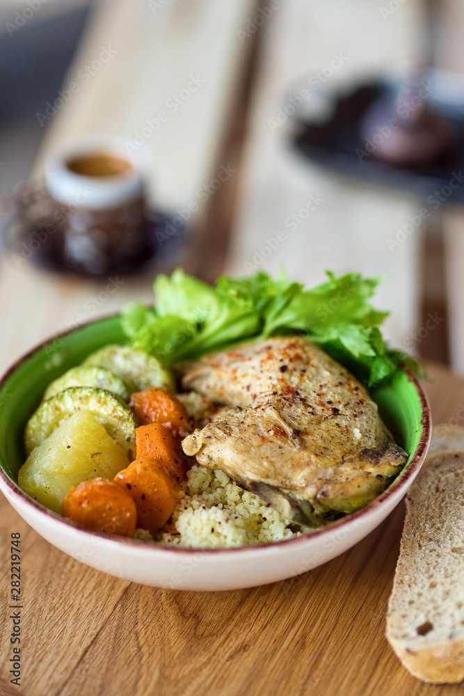 Boiled chicken leg and potatoes with zucchini, carrots and herbs served with bread and coffee on a wooden background Boiled chicken leg and potatoes with zucchini, carrots and herbs served with bread and coffee on a wooden background