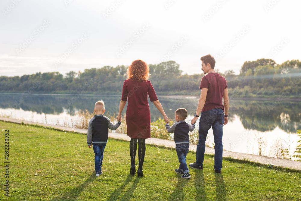 Parenthood and nature concept -Family of mother and father with two boys twins kids in a park at summer by a river at sunny day
