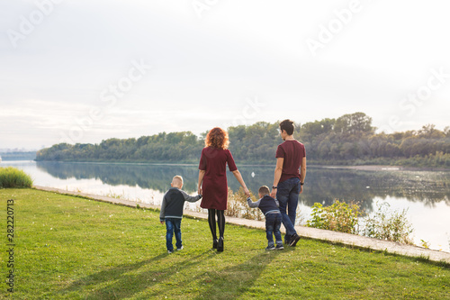 Childhood and nature concept - Family walking by the water