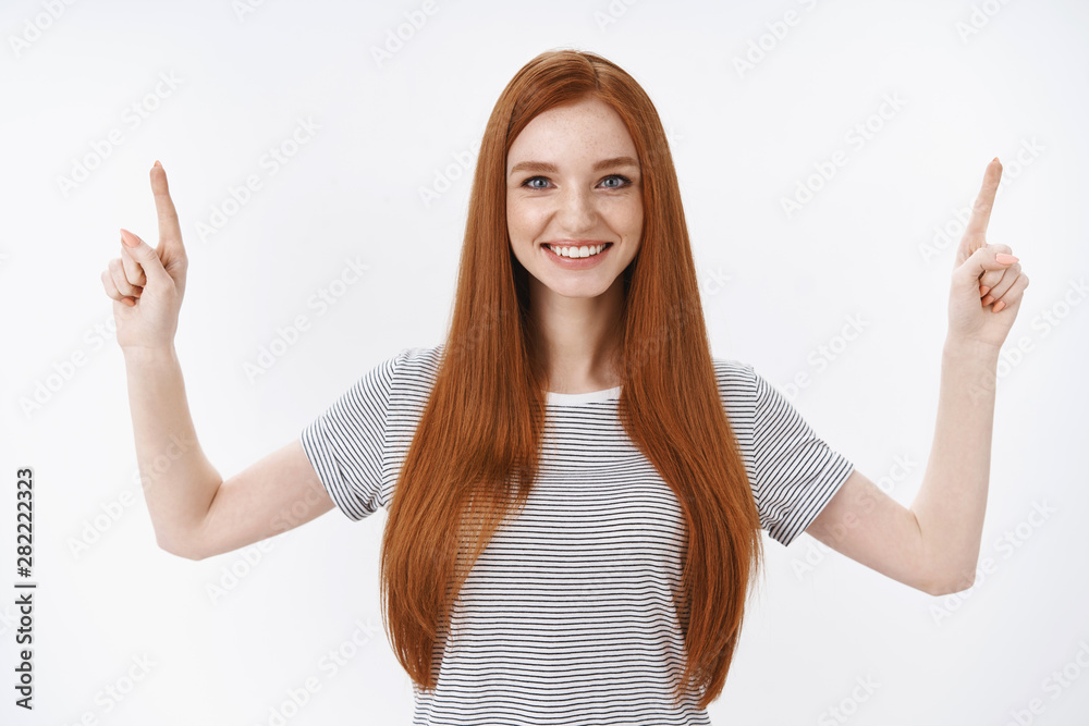 Confident attractive friendly happy young ginger girl blue eyes wearing striped t-shirt smiling white teeth raising index fingers pointing up self-assured, showing good option recommend promo Confident attractive friendly happy young ginger girl blue eyes wearing striped t-shirt smiling white teeth raising index fingers pointing up self-assured, showing good option recommend promo