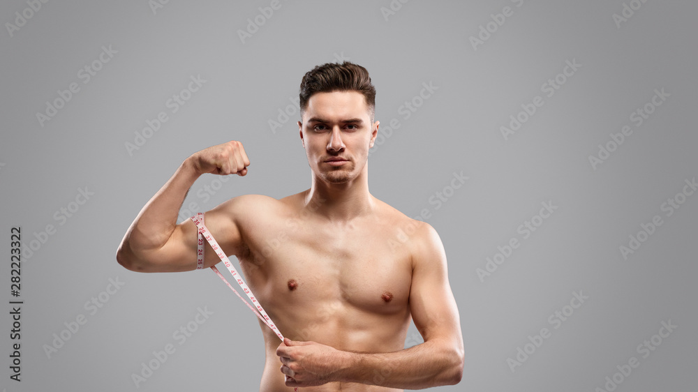 Fototapeta premium Serious guy measuring arm muscles