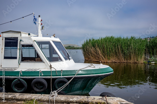 Street view with tourist boat mooring, Ioannina island on lake Pamvotida near the beautiful small island near the Greek town of Ioannina. Early morning foggy dark spring day scene photo