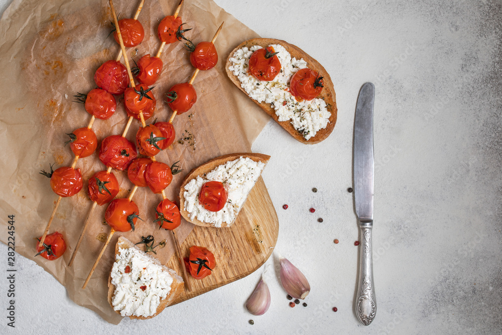 Grilled cherry tomatoes on skewers, on baking paper. Italian bruschetta with tomatoes and cheese Grilled cherry tomatoes on skewers, on baking paper. Italian bruschetta with tomatoes and cheese