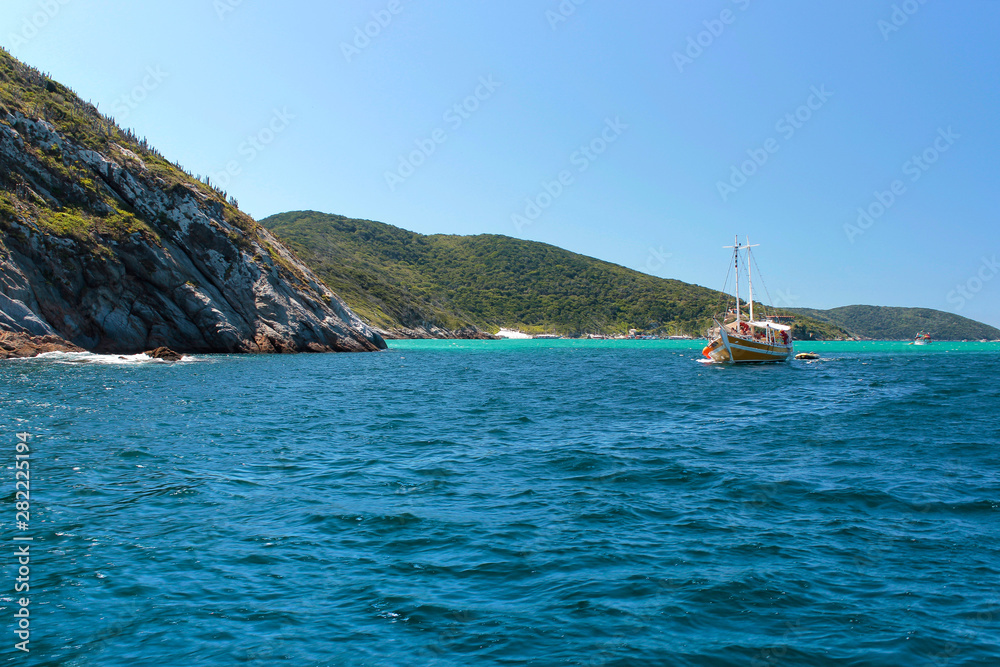 ARRAIAL DO CABO,  RIO DE JANEIRO, BRAZIL- MARCH 21, 2016: Sailboat and a boat over a green and clear waters near a coast. 