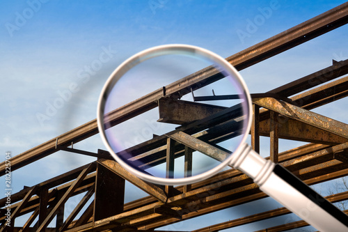 Old metal structure of an abandoned factory built with beams and metal profiles - Concept image seen through a magnifying glass