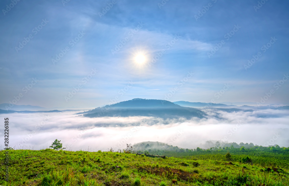 Naklejka premium Dawn on a mountain plateau Da Lat, Vietnam beneath mist covered valleys and the sun rising over sky filled yellow color. 