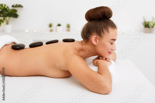 Relaxed woman enjoying hot stone massage in spa