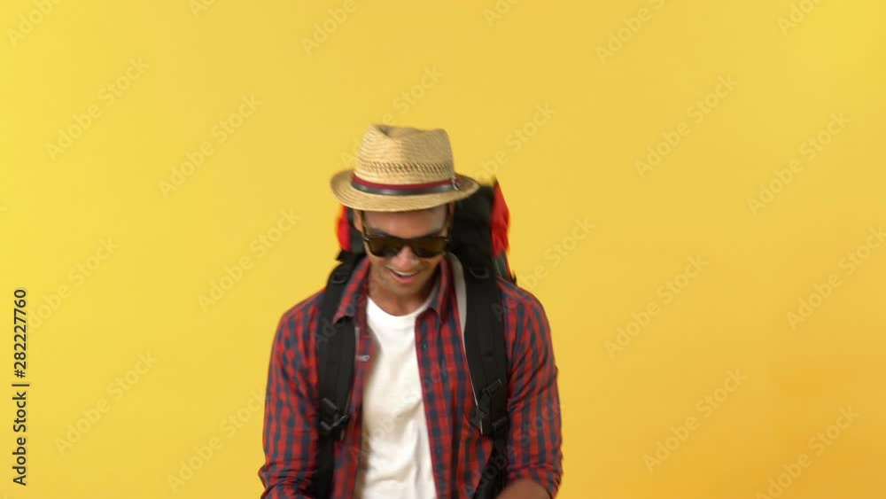 Portrait of smiling indian tourist man with backpack dancing with joy against yellow backdrop Portrait of smiling indian tourist man with backpack dancing with joy against yellow backdrop