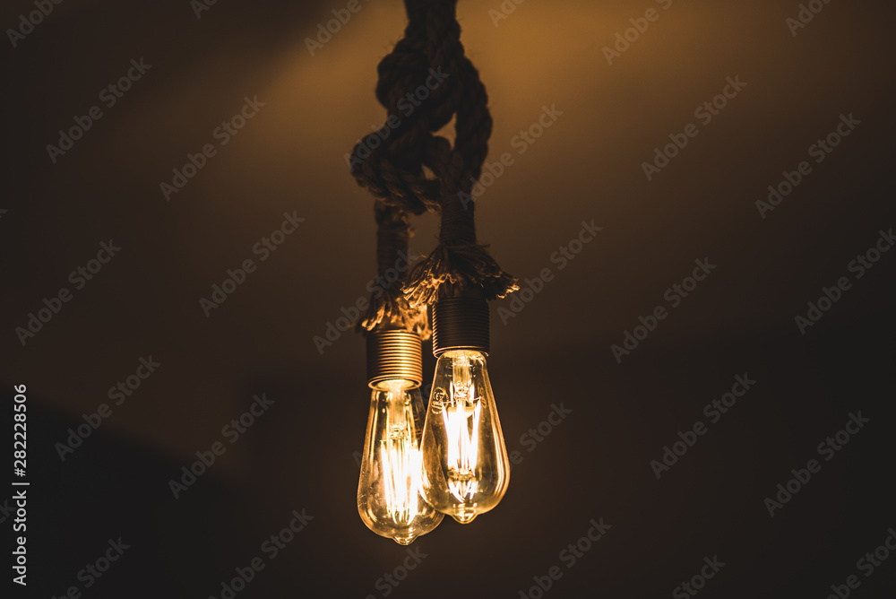 White and moody Vintage style lamp with two lightbulbs hanging on a thick rope  looking antique 