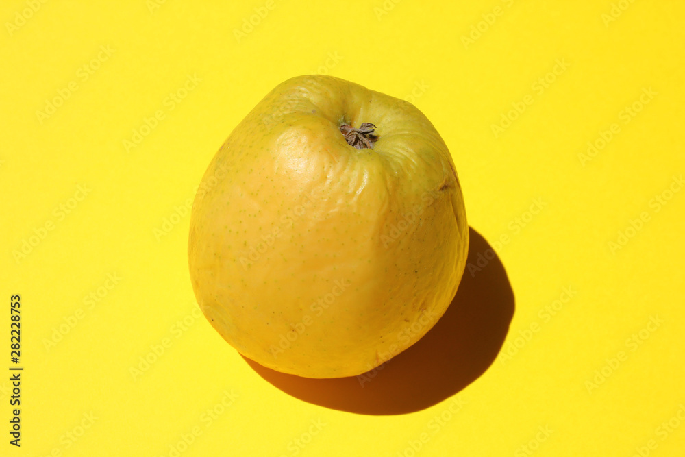Fototapeta premium Ripe yellow apple on yellow background