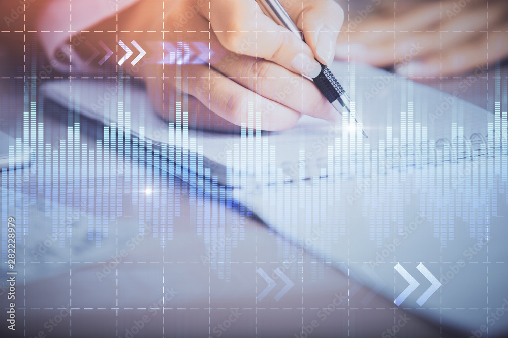 A woman hands writing information about stock market in notepad. Forex chart holograms in front. Concept of research. Multi exposure A woman hands writing information about stock market in notepad. Forex chart holograms in front. Concept of research. Multi exposure