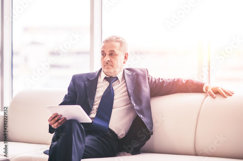 successful businessman with digital tablet sitting on sofa in the office.