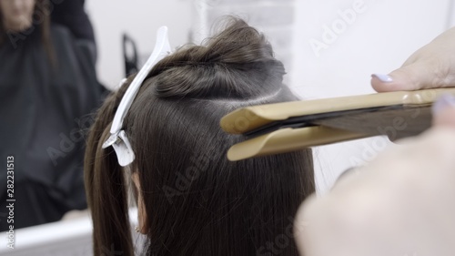Cute girl with long brunette hair hairdresser doing hair lamination in a beauty salon. concept of hair care treatment 