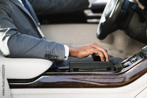 Businessman driving car, holding hand on gearbox