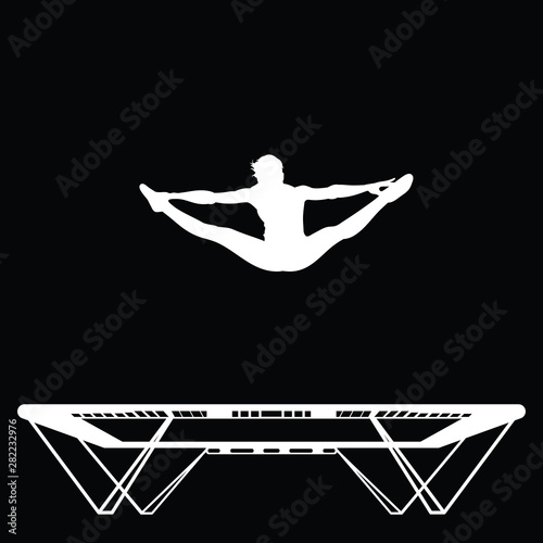 Young sportsman is doing straddle jump on a trampoline, silhouette