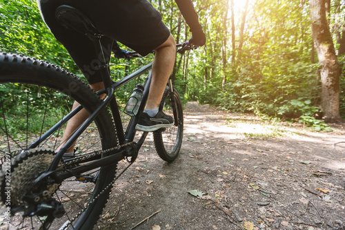 Legs of caucasian man riding bike in the forest