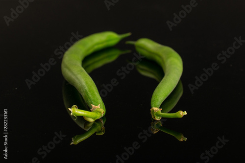Group of two whole fresh green bean isolated on black glass