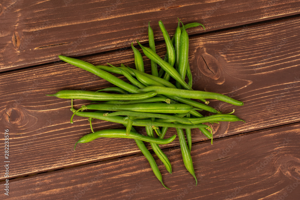 Lot of whole fresh green bean flatlay on brown wood Lot of whole fresh green bean flatlay on brown wood