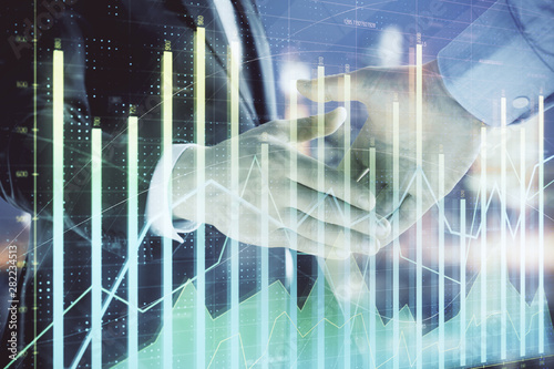 Double exposure of financial chart on cityscape background with two businessmen handshake. Concept of financial analysis and investment opportunities