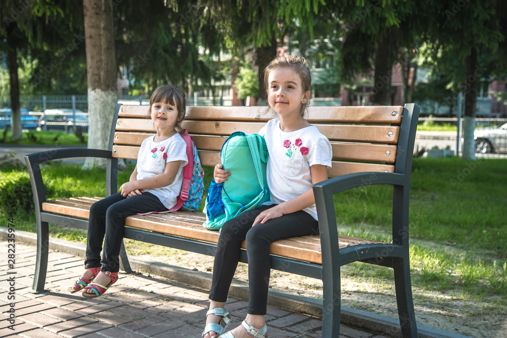 Back to school. Happy cute industrious kids sitting on the bench and talking. Concept of successful education. Back to school. Happy cute industrious kids sitting on the bench and talking. Concept of successful education.