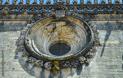 Round window with a beautiful ornament on the wall of an ancient monastery 