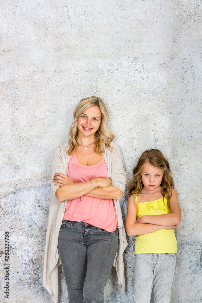 pretty, blonde young mother poses and cuddles with her daughter in front of a concrete wall and having a lot of fun pretty, blonde young mother poses and cuddles with her daughter in front of a concrete wall and having a lot of fun