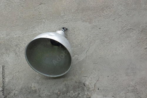 Industrial lantern or street lamp on concrete building wall. Silver reflector of lighting system is screwed to surface with scratches and cracks. Weathered texture background with copy space photo