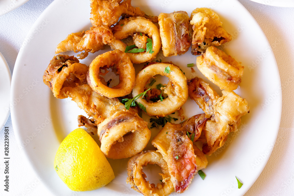 Top view of seafood meal. Fried squids with slice of lemon. Top view of seafood meal. Fried squids with slice of lemon.