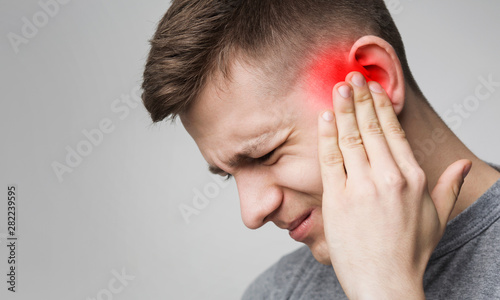 Young man has sore ear, suffering from otitis photo