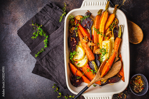 Baked vegetables with thyme in the oven dish, dark background. photo