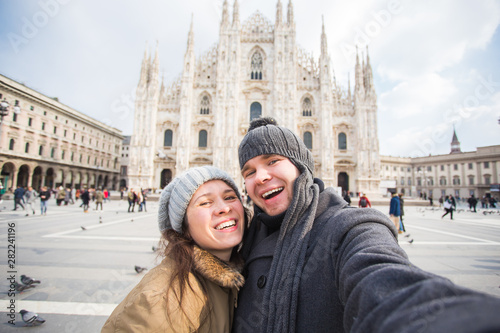 Travel, Italy and funny couple concept - Happy tourists taking a self portrait in front of Duomo cathedral, Milan