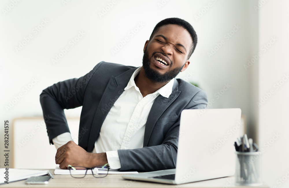 African businessman holding his side, suffering from liver pain African businessman holding his side, suffering from liver pain