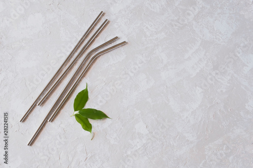 Reusable stainless steel metallic straws on neutral background with copy space. 