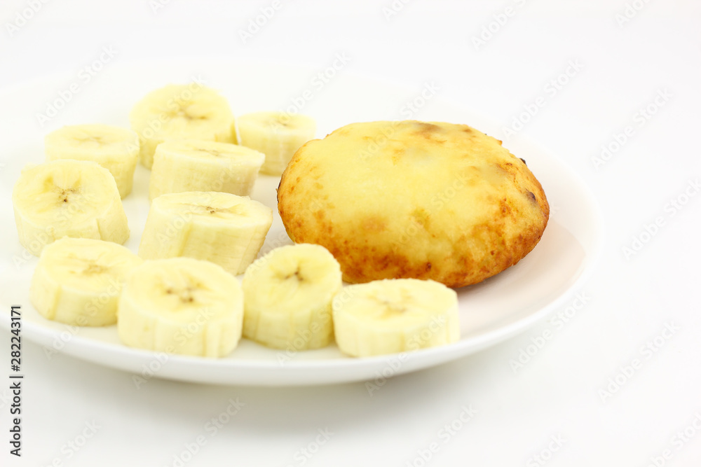 Cheesecake oval on a white plate with sliced banana pieces