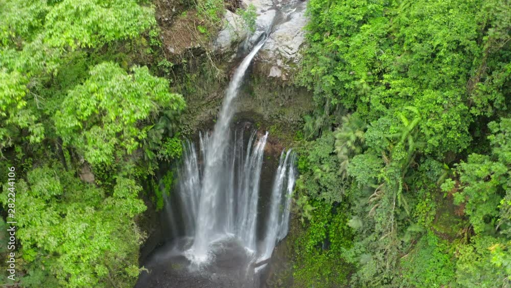 Aerial: Fresh Water Plummeting Onto Rocks From the Tiu Kelap Waterfall in the Tropical Jungle in Bali - Lombok, Bali Aerial: Fresh Water Plummeting Onto Rocks From the Tiu Kelap Waterfall in the Tropical Jungle in Bali - Lombok, Bali