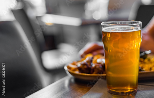 glass of cold beer and plate with snacks on wooden table background on bar or pub