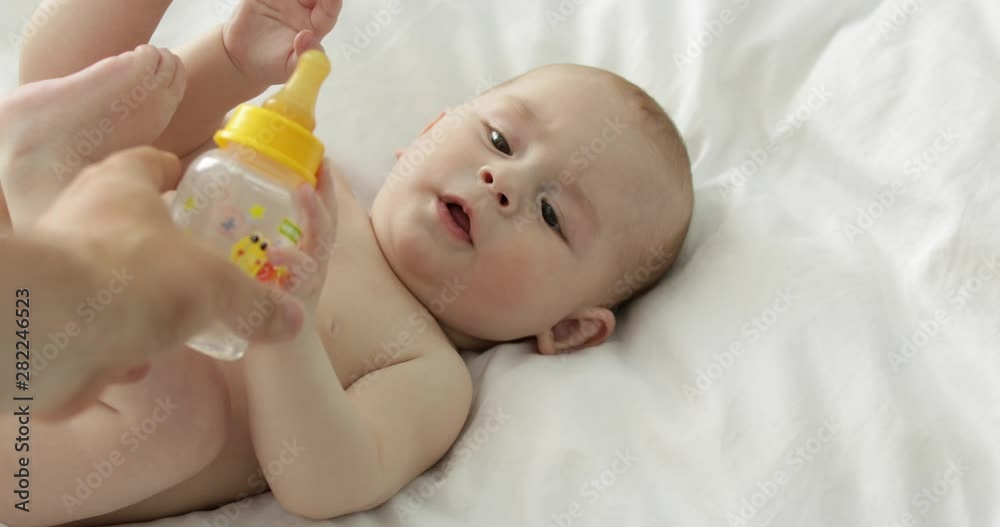 Adorable little child drinking water on bed at home Adorable little child drinking water on bed at home