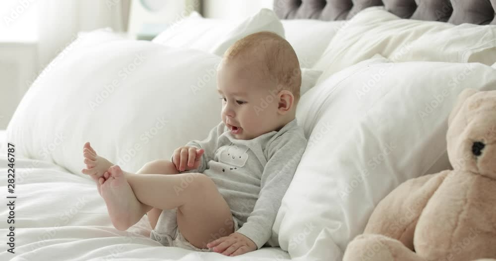 Adorable little child sitting on bed at home Adorable little child sitting on bed at home