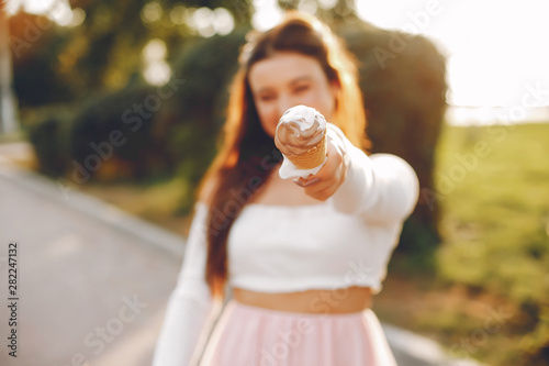 Beautiful girl in a park. Lady have fun in a summer city. Girl with an ice cream